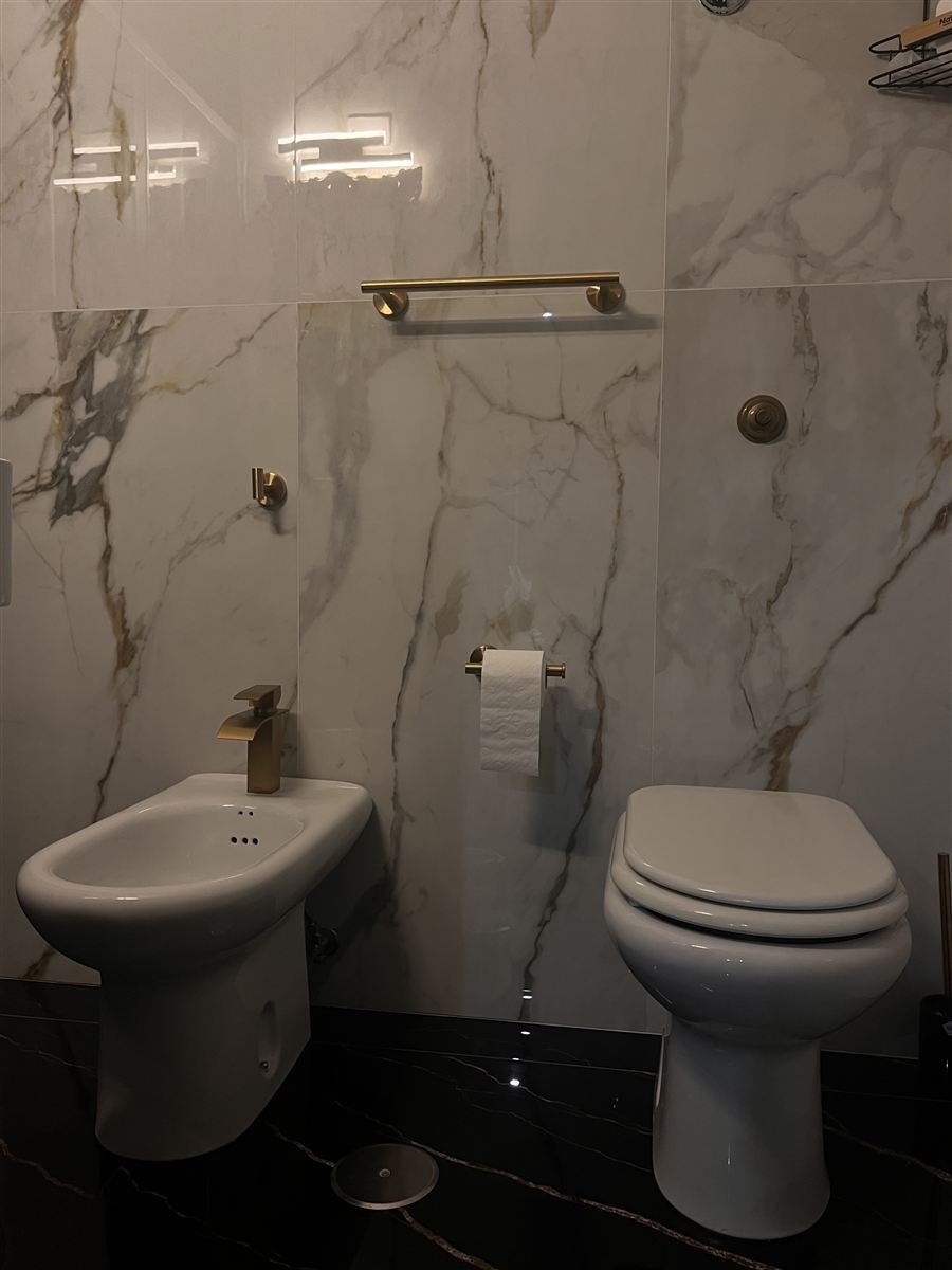 Sanitari in marmo chiaro con rifiniture oro spazzolato